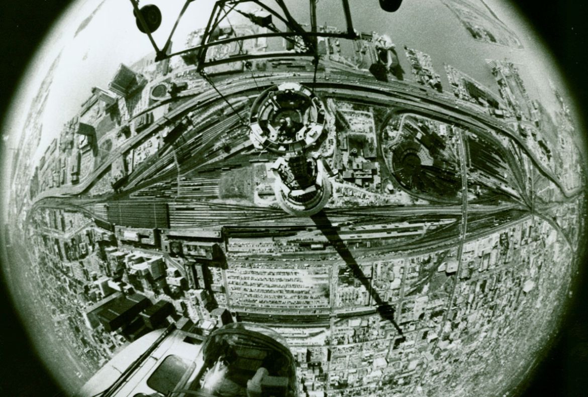 A photo taken from a helicopter using a fish-eye lens shows the Tower’s antenna being topped in March 1975.