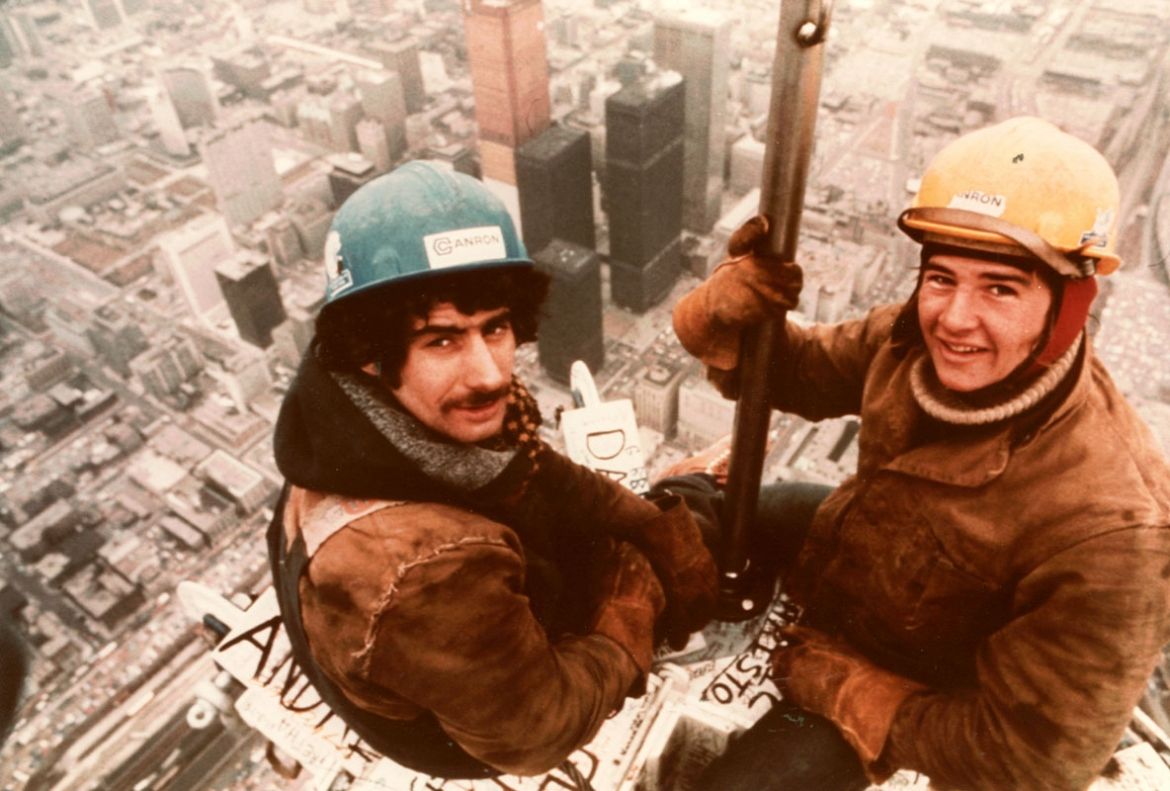 Two construction workers on the top of the CN Tower are seen overlooking the city in April 1975.