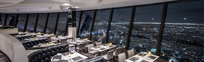 The interior of the 360 restaurant at the CN Tower. The city lights at night are visible through the windows