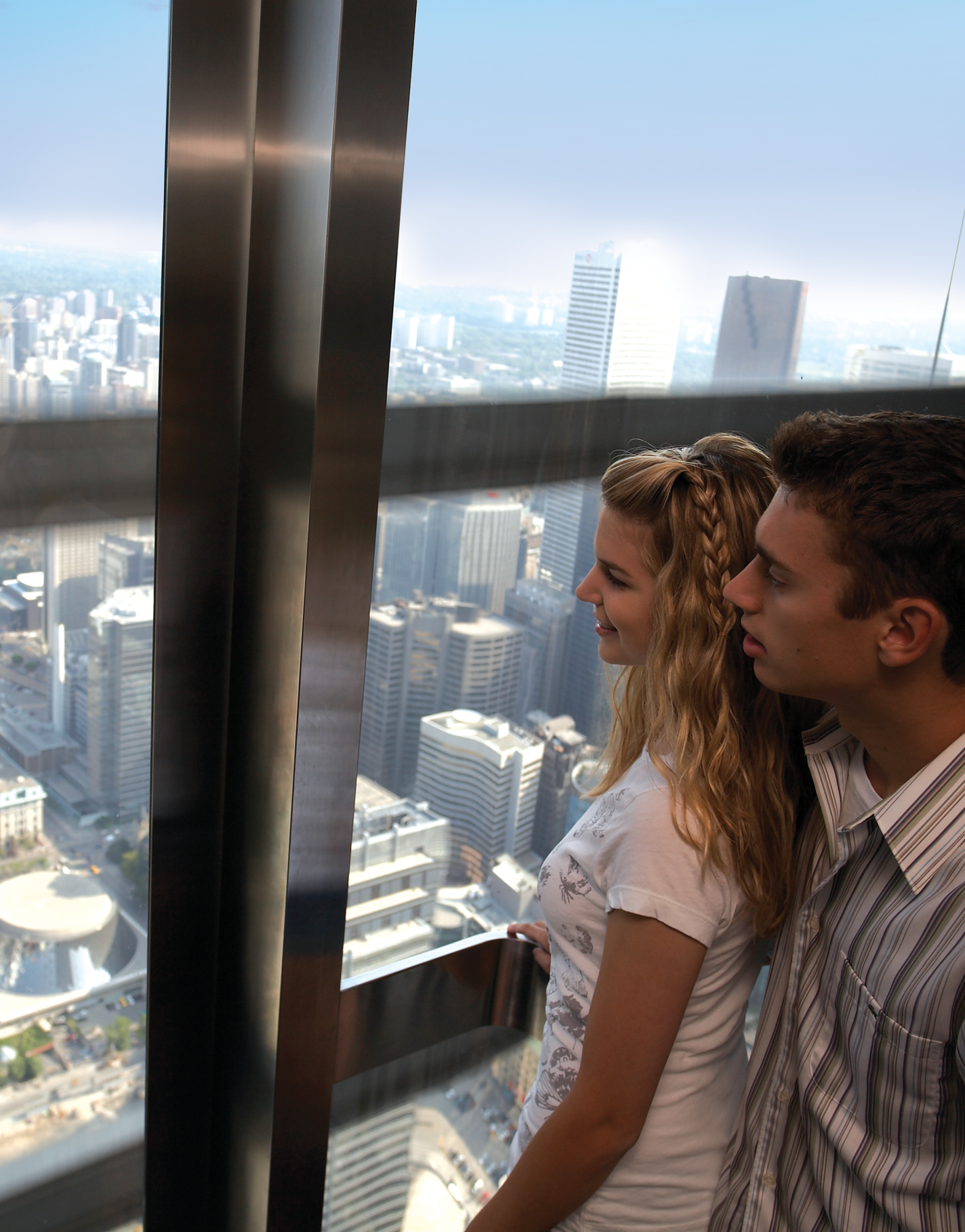 Two people looking through the window of the elevator. The city in the background.