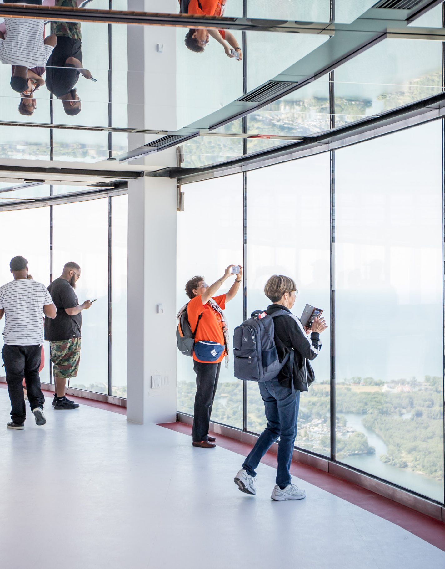 Two people looking out the window. Holding cell phones in their hands to take photo