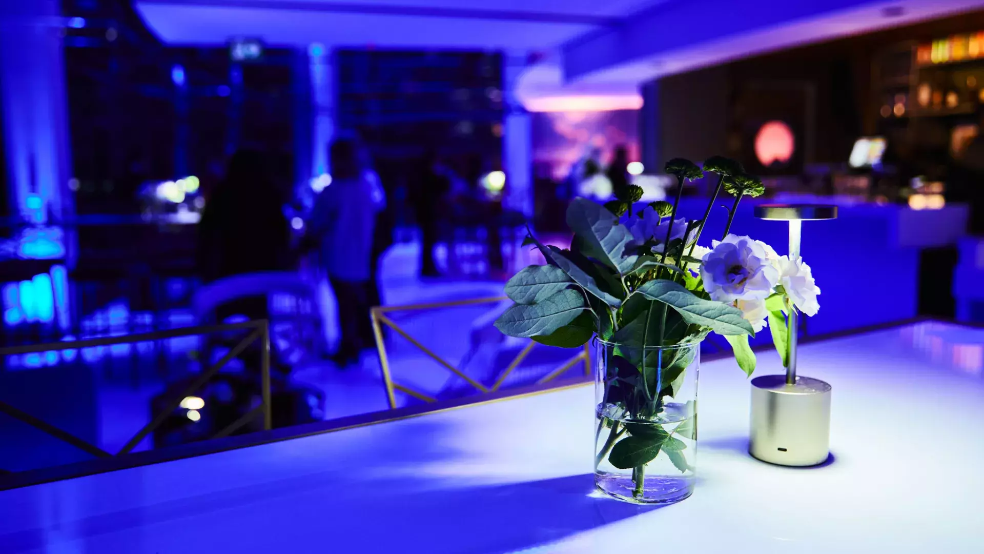 view of a vase of flowers and light on a table during an event at the CN Tower. The atmosphere is dark with a purple tint.