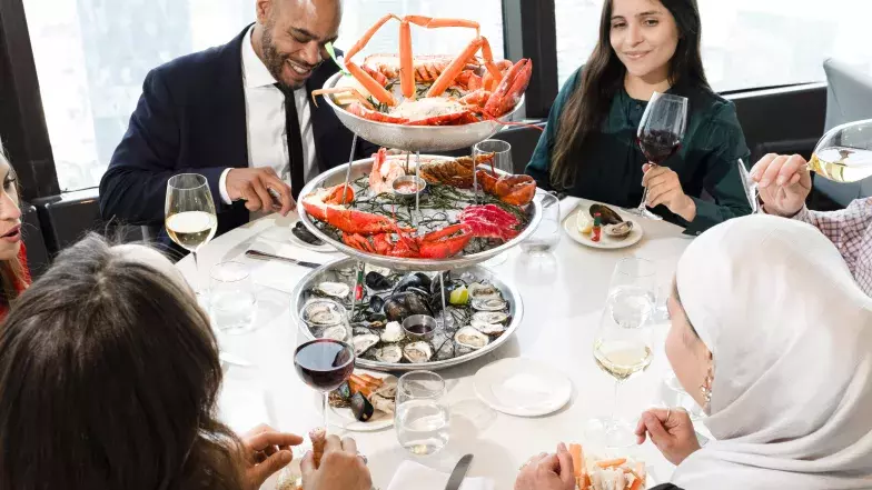 Group sharing a 3 tiered seafood tower at 360, filled with lobsters, mussels, oysters and crab