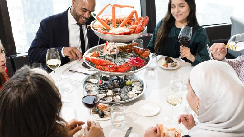 Group sharing a 3 tiered seafood tower at 360, filled with lobsters, mussels, oysters and crab