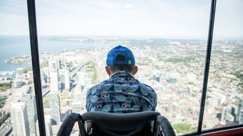 person in a wheelchair looking out the window at CN Tower