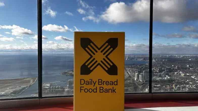 Yellow Daily Bread Food Bank donation box on the CN Tower’s Main Observation Level with views of west Toronto