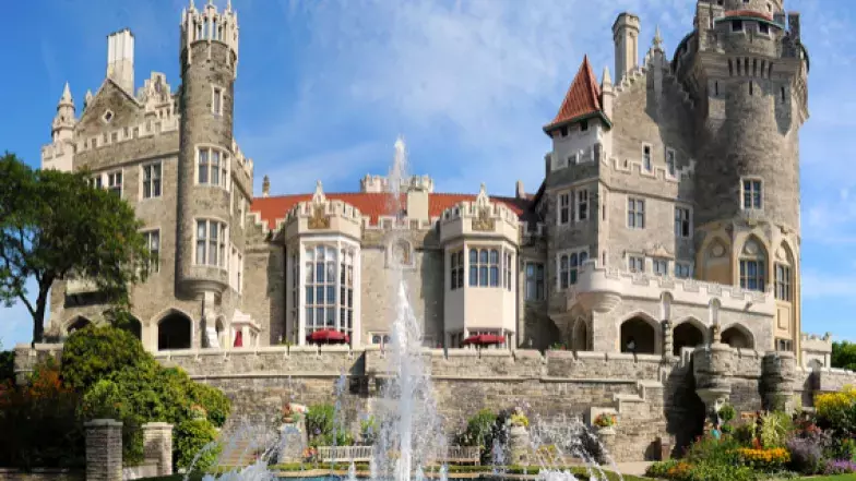 water fountain in front. Big brick building in the background with towers and chimneys at the top
