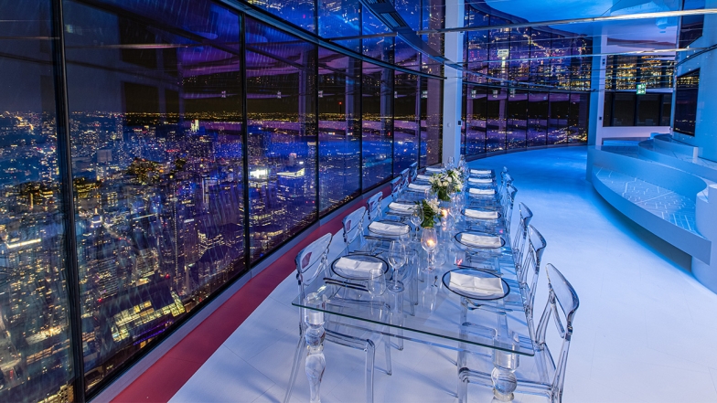 Chairs and table set up along the window with the view of Toronto at night