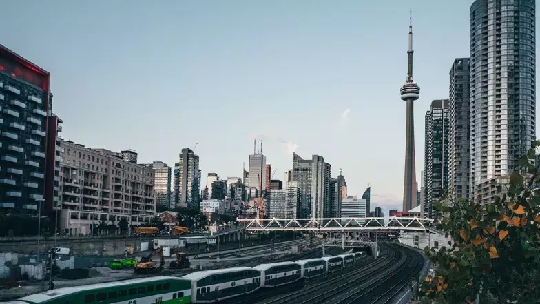 CN Tower in the background and the Go Train and train tracks in the foreground