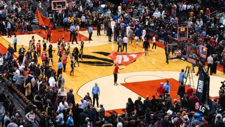 View of the basketball court from above. Crowd of people in the stands and a cheerleading team on the floor.