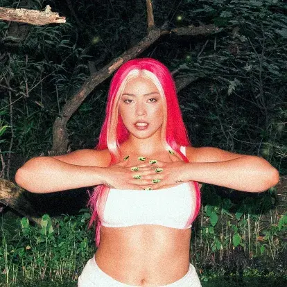 Headshot of Semiah Smith standing outside in a white outfit and bright magenta hair.