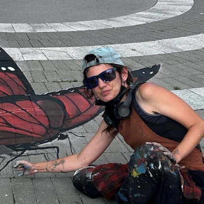 jo the chalk chick crouching down next to their 3D butterfly mural